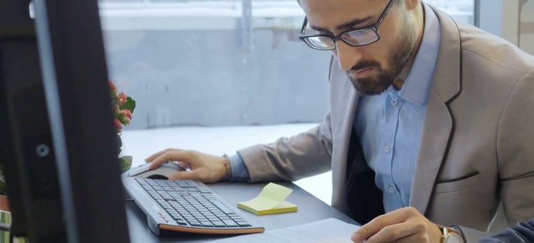 businessman looking at document next to computer