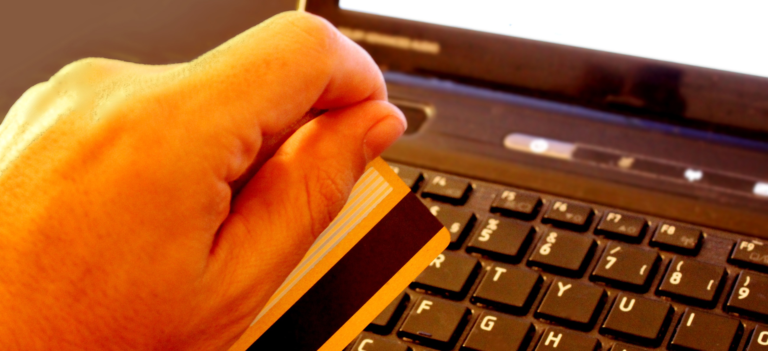 holding bank card next to computer