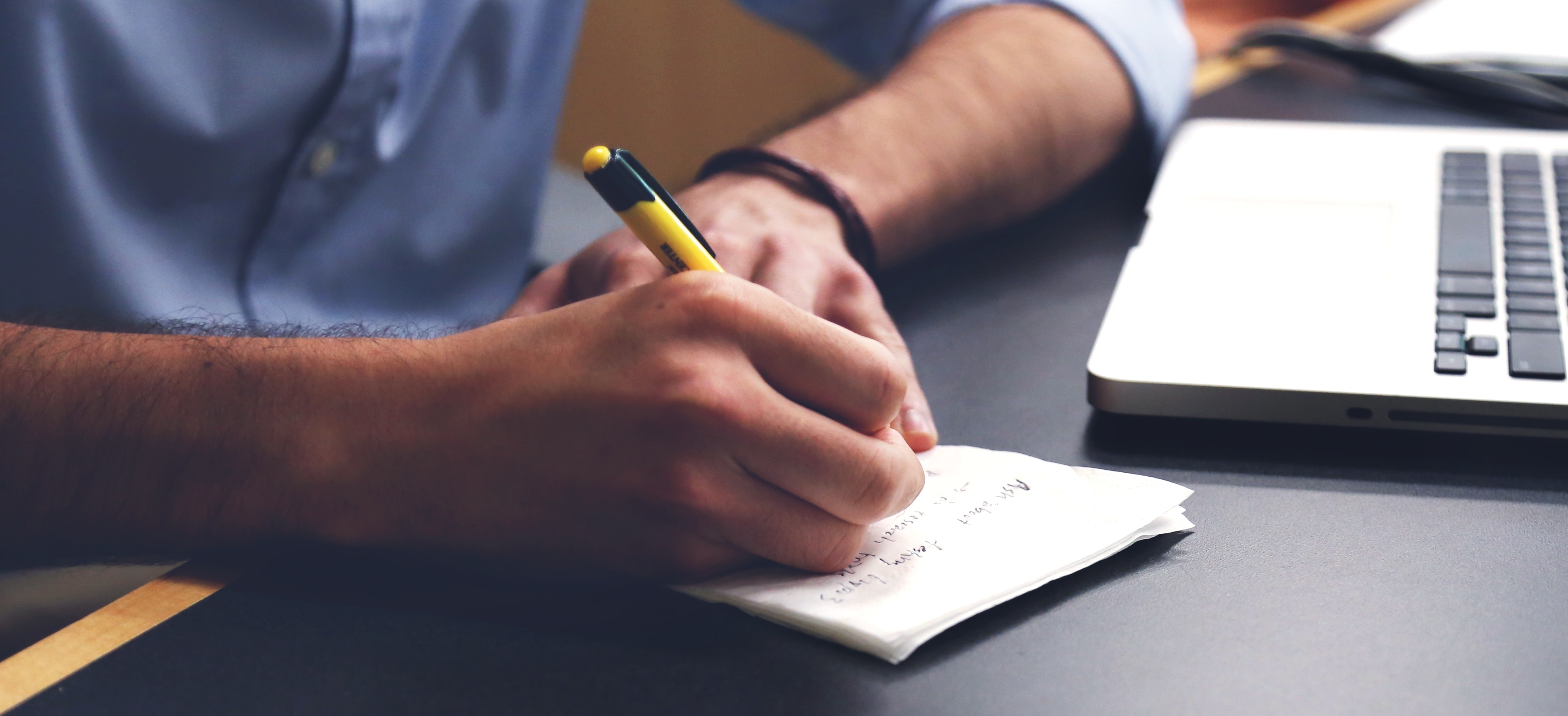 man writing information from a computer onto paper