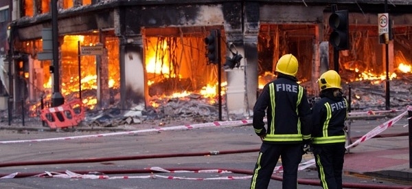 firemen standing in front of a burning building